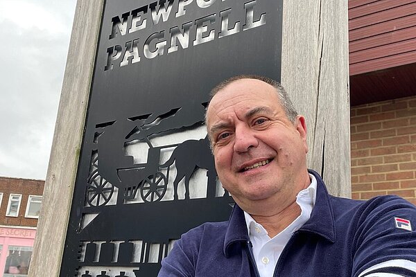 Photo of Scott Humphries in front of a Newport Pagnell Sign