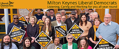 A group of Liberal Democrats holding Lib Dem diamond posters