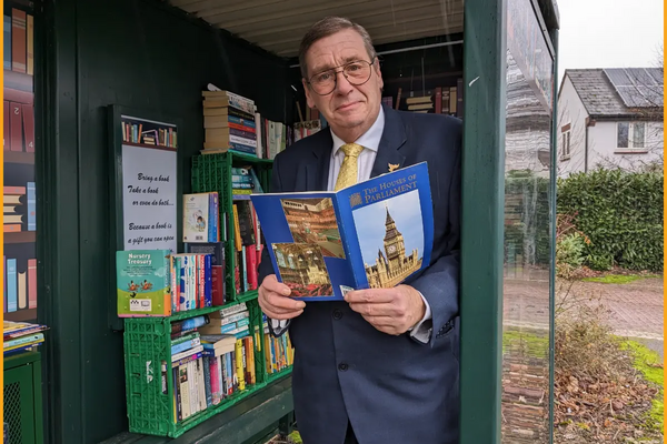 Councillor Paul Trendall shows a local bus stop which has been converted to a free book exchange for residents