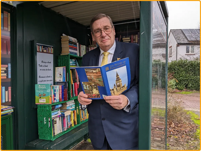 Councillor Paul Trendall shows a local bus stop which has been converted to a free book exchange for residents